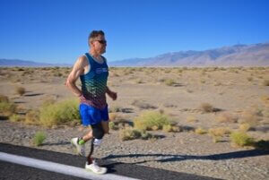 A white man with a disability is running in the desert.